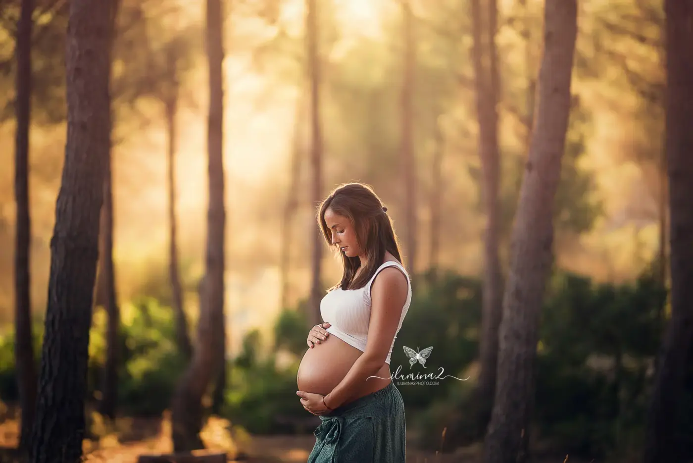 Mamá mirando su barriga en su sesión de embarazo en el bosque