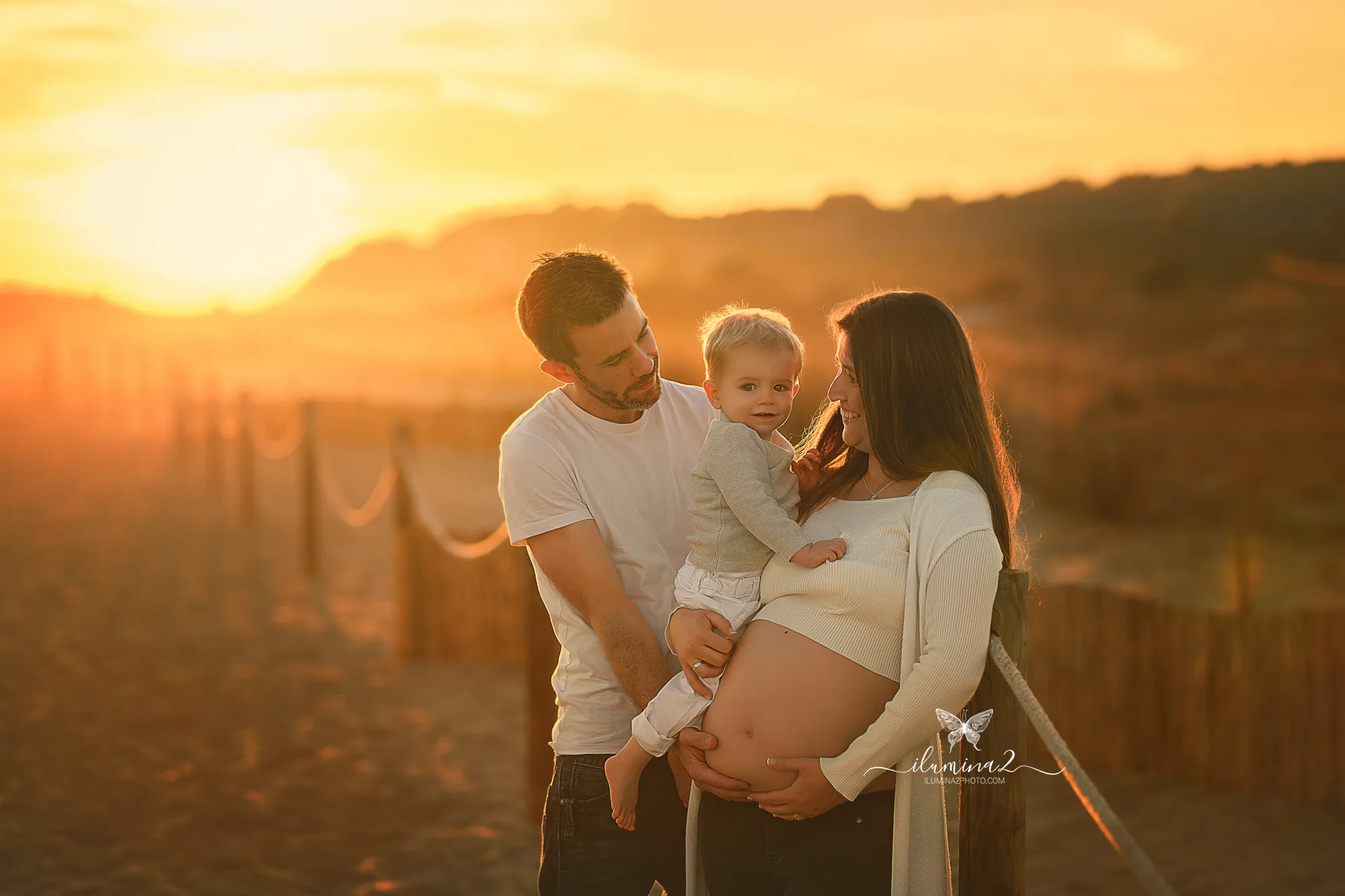 Familia en una sesión de embarazo en la playa al atardecer en Barcelona