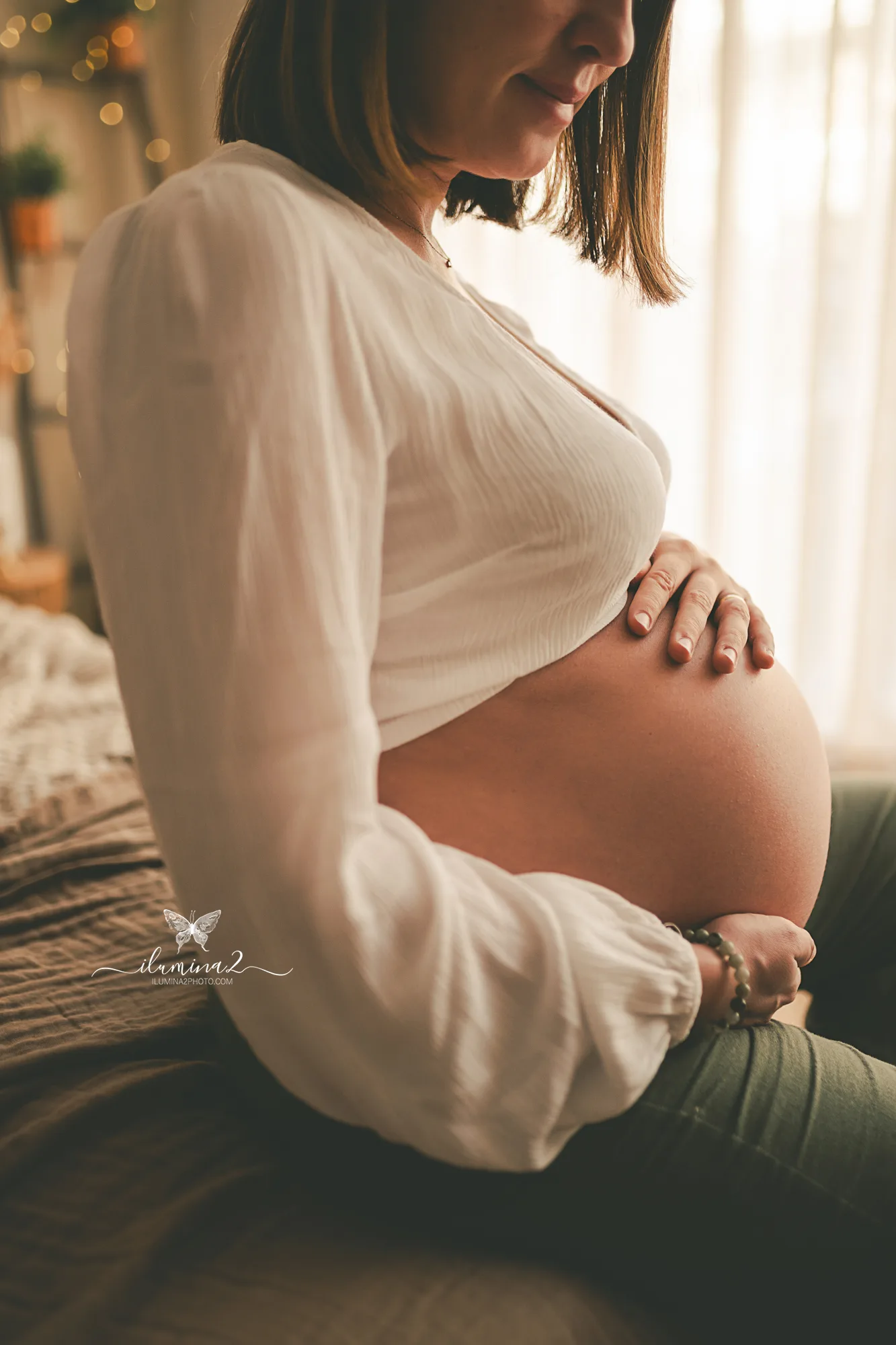 Detalle de las manos de una embarazada sobre la barriga con luz natural suave