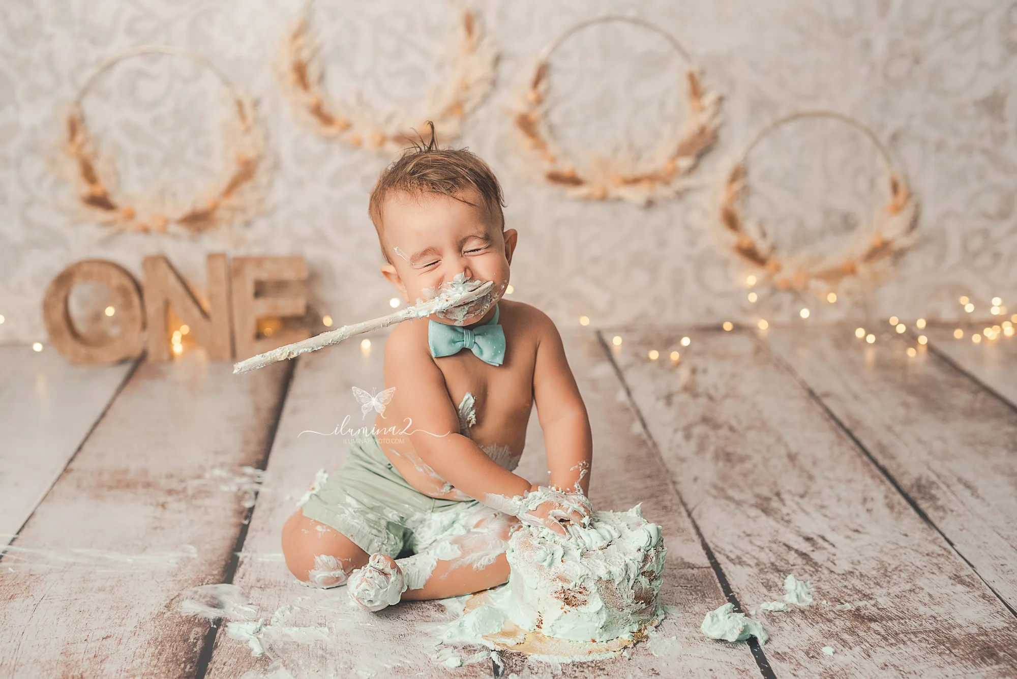 Bebé riendo con una cuchara mientras juega con su tarta en una sesión Smash Cake en Barcelona