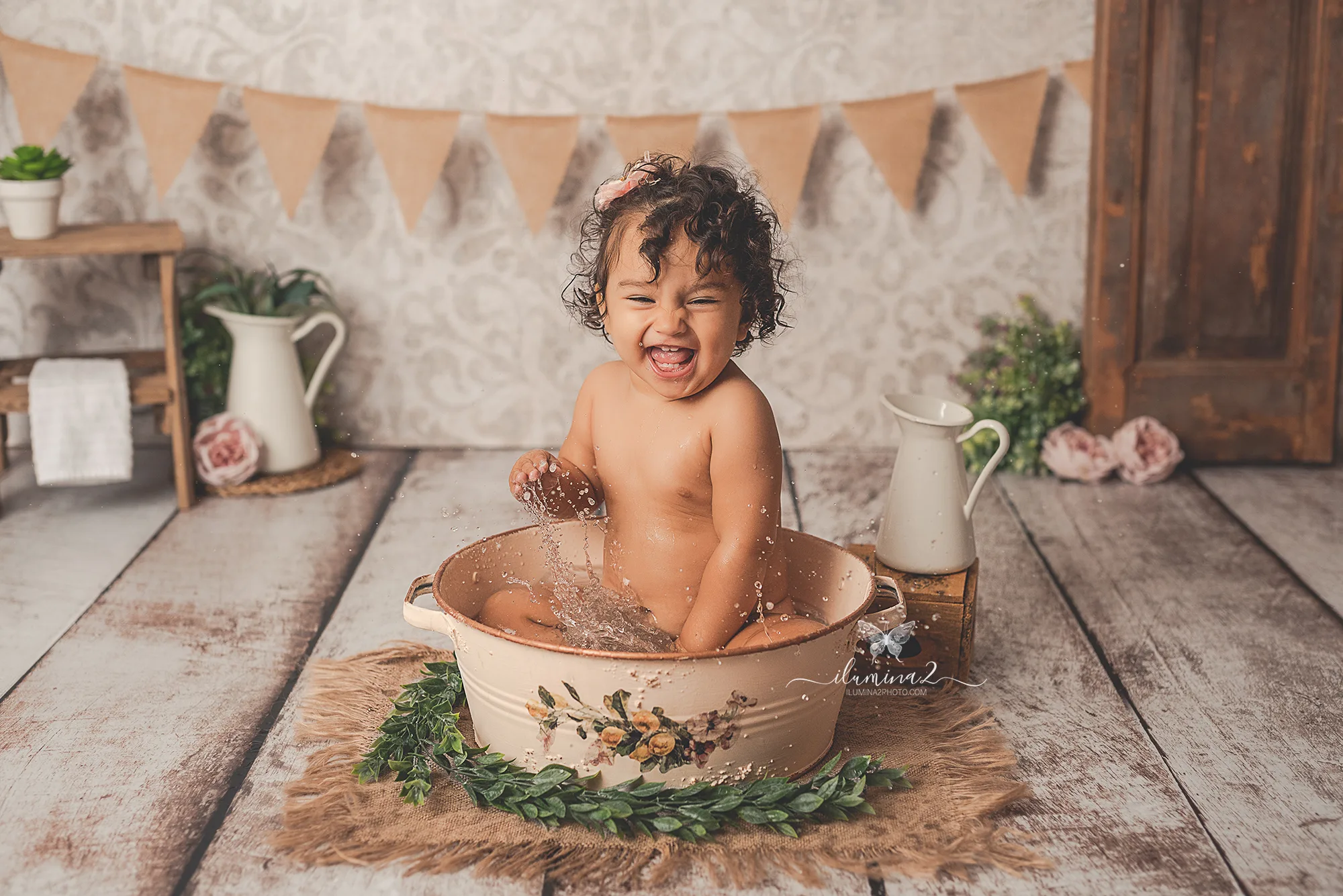 Bebé riendo y salpicando agua en el baño posterior a su sesión Smash Cake