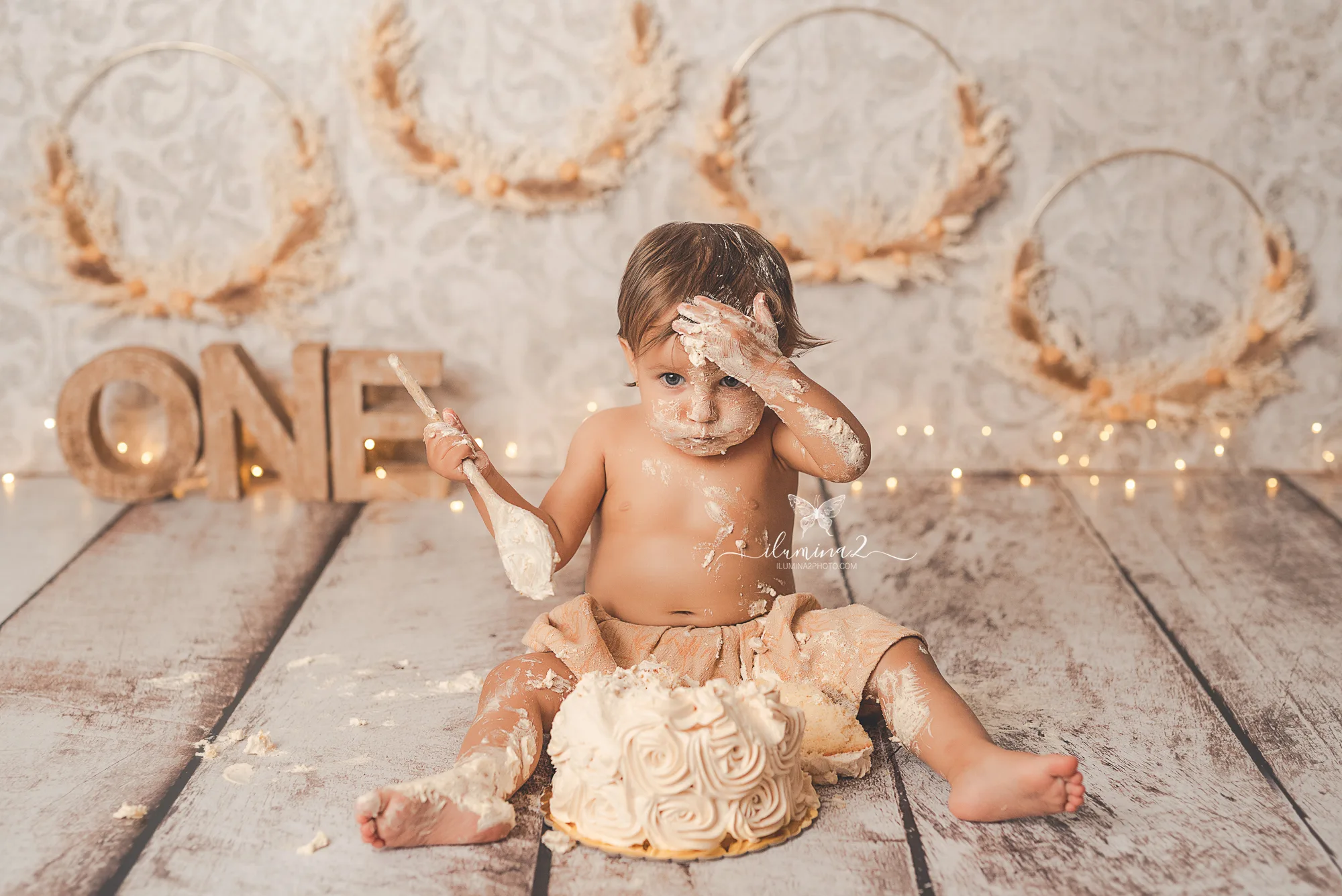 Bebé jugando con su pastel al final de un reportaje Smash Cake de primer cumpleaños
