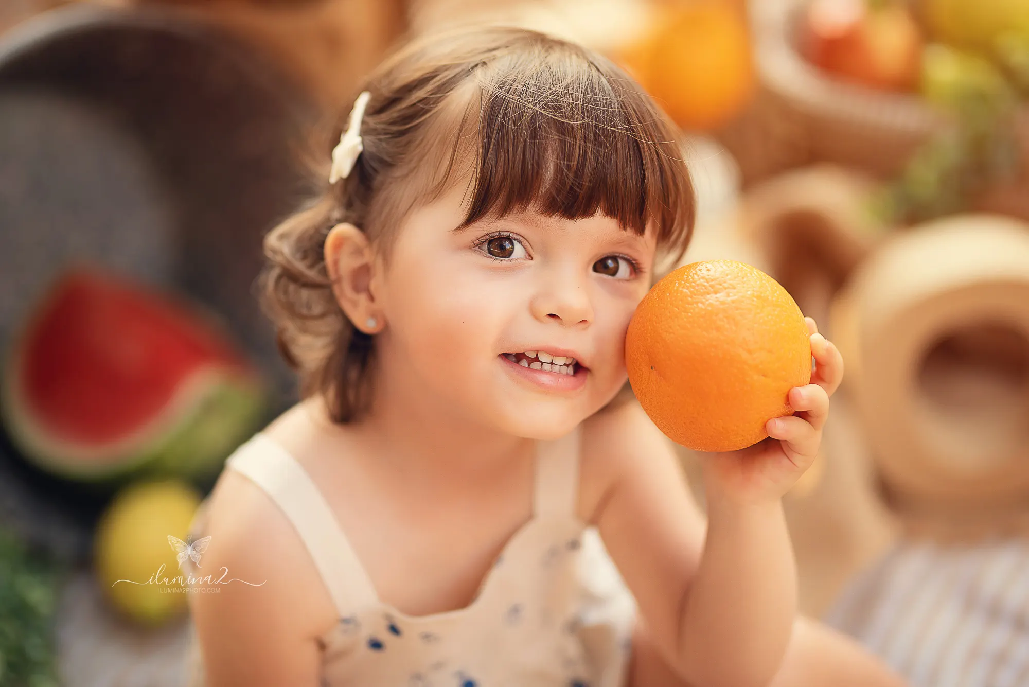 Bebé sosteniendo una naranja en una sesión Smash Cake con fruta natural