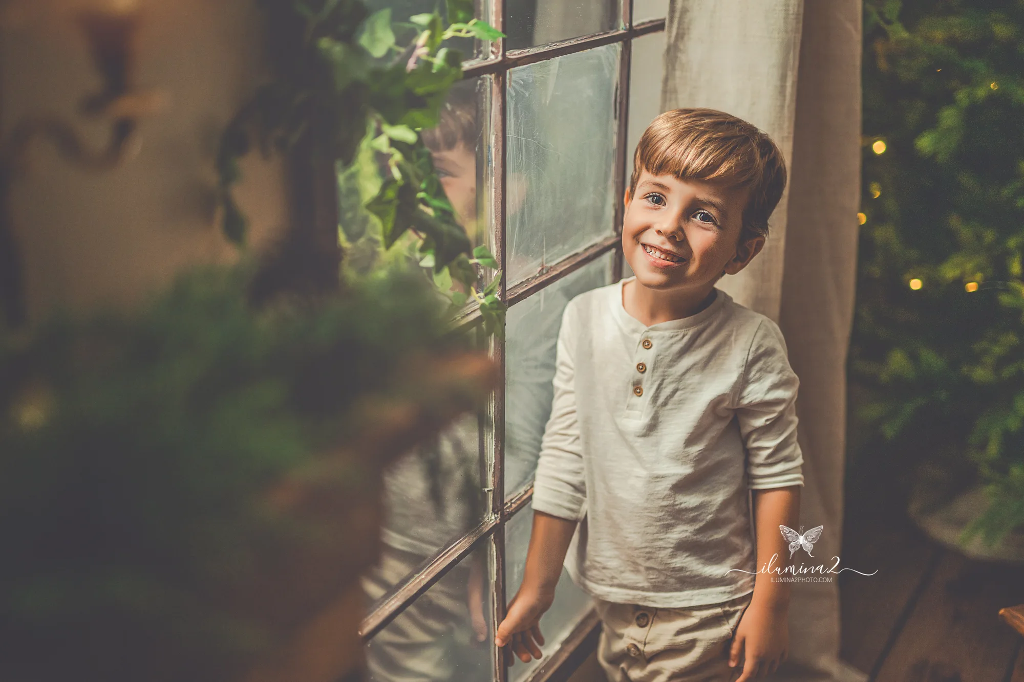 Sesiones de fotos de Navidad Ilumina2 Photo Detalle de un niño contento junto a una ventana del decorado navideño en Barcelona