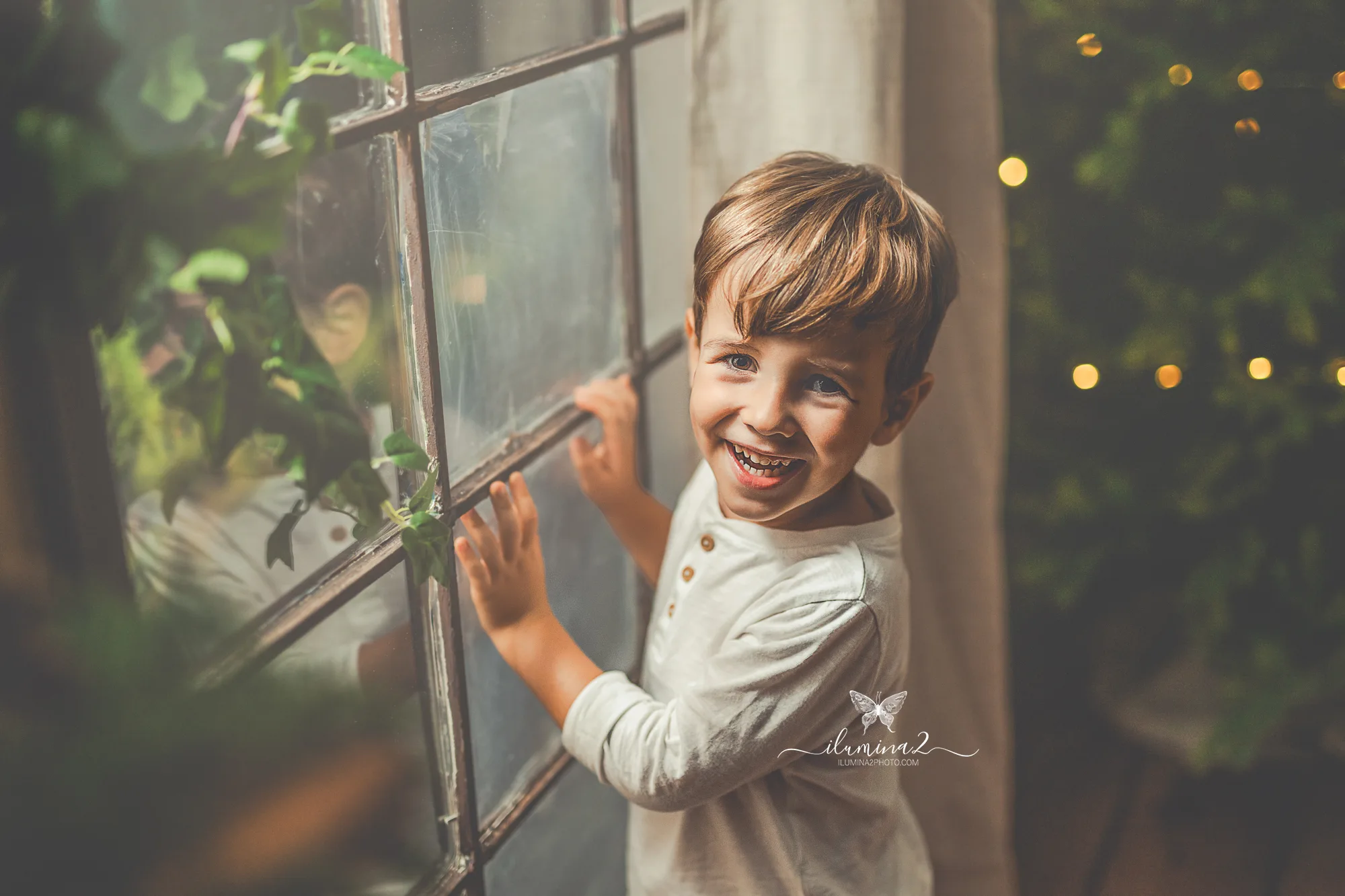 Sesiones de fotos de Navidad Ilumina2 Photo Mini sesión de navidad para niños en Barcelona. Niño junto a una ventana descubriendo el decorado de Navidad.