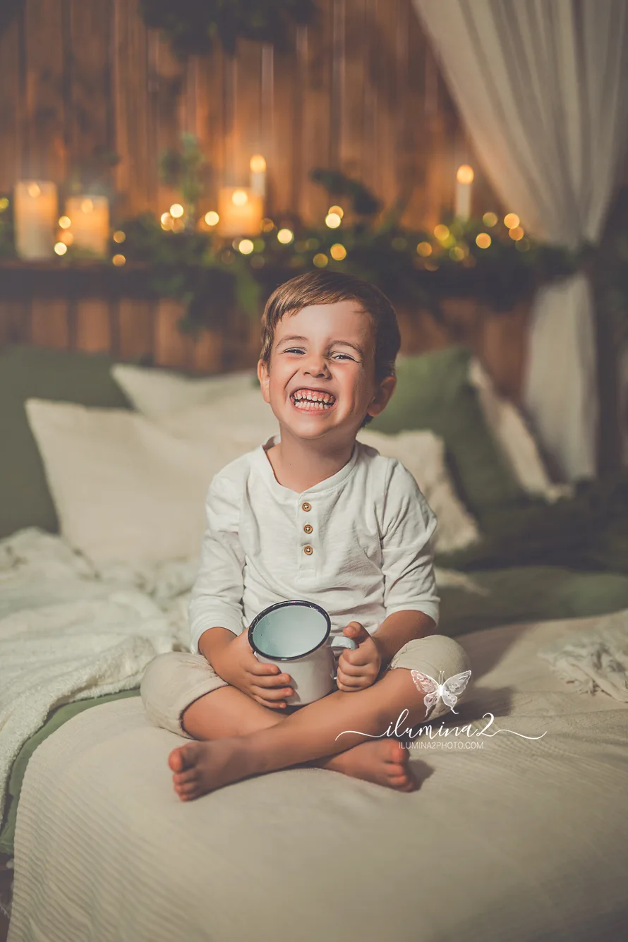 Sesiones de fotos de Navidad Ilumina2 Photo Niño riendo sobre la cama en su reportaje de Navidad en Barcelona