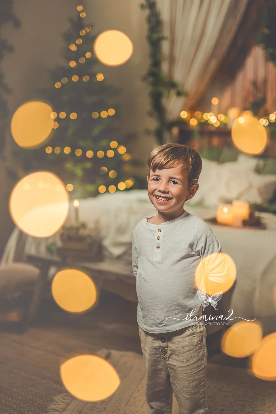 Sesiones de fotos de Navidad Ilumina2 Photo Niño en su reportaje fotográfico de Navidad rodeado por un bonito bokeh de luces navideñas