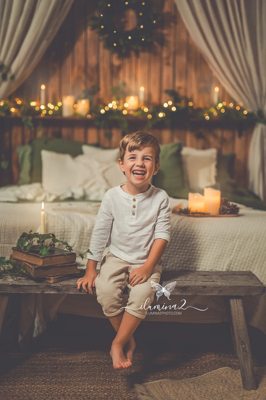 Niño mirando a cámara entre lucecitas de la habitación en un reportaje de fotos de Navidad en estudio