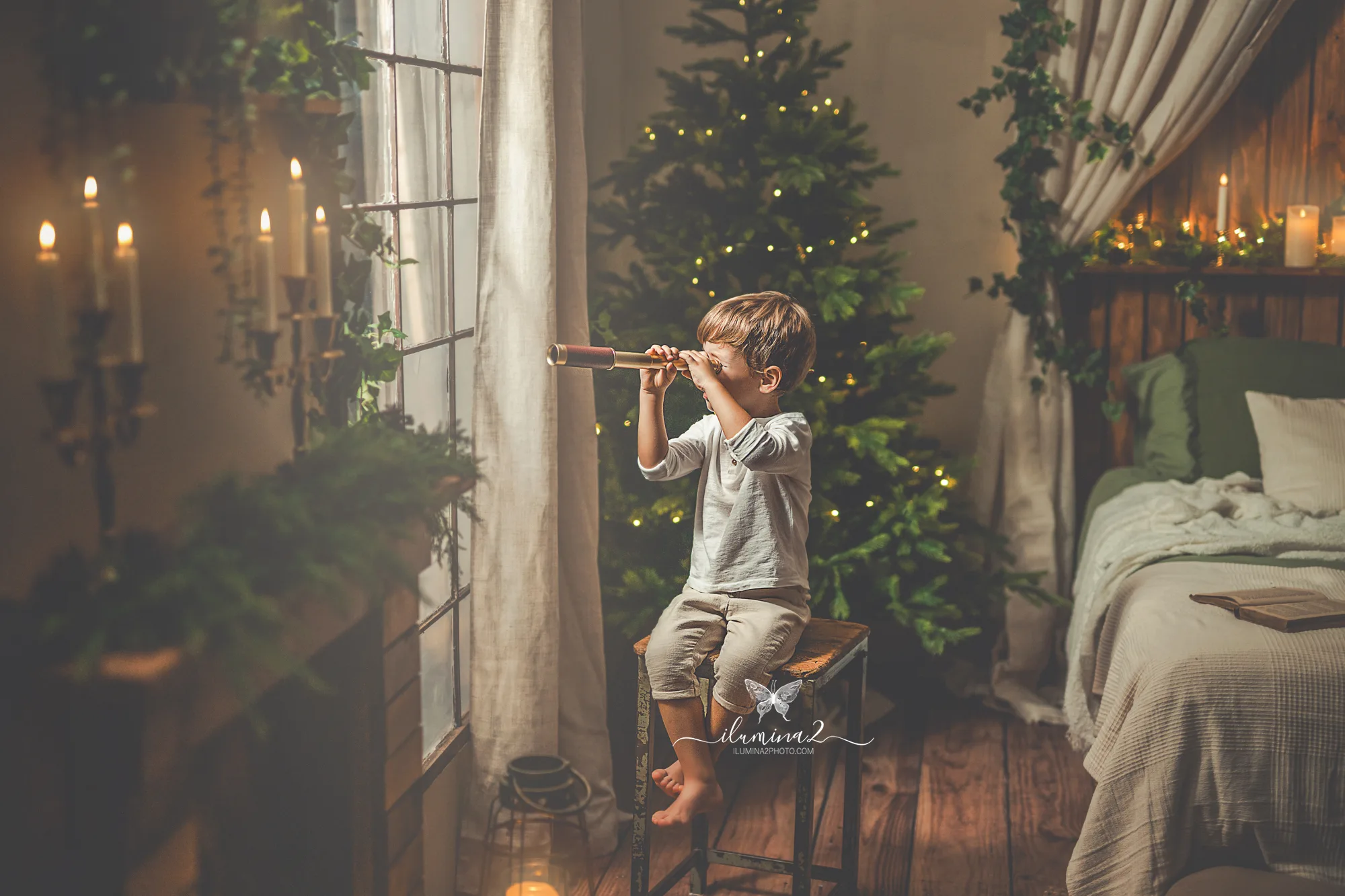 Niño mirando por la ventana con un catalejo en su sesión de Navidad